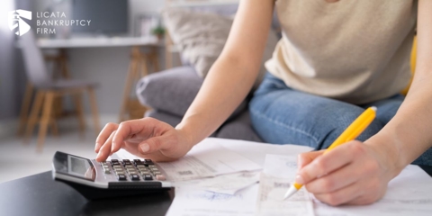 Woman calculating payments while holding a pen and using a calculator
